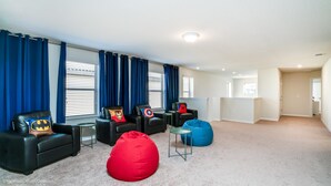 A living room with black leather sofas, red and blue bean bags, and superhero-themed pillows. - Solterra Exec Villas- 5445misty (Davenport)