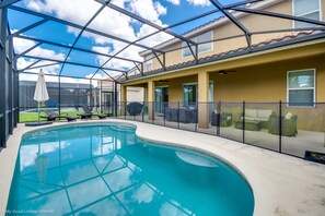 A swimming pool with a glass enclosure, a covered patio area, and a view of a residential building. - Solterra Exec Villas- 5196oa (Davenport)