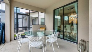 A glass-top table with white chairs in a covered outdoor area with a ceiling fan. - Solterra Exec Villas- 5416sc (Davenport)