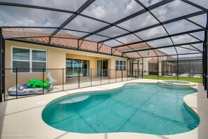 Una piscina de borde curvo, rodeada por un patio techado con estructura de techo metálico.