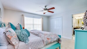 A bedroom with a bed, a ceiling fan, a window with curtains, and a door. - Storey Lake Exec Villas- 3175pp (Kissimmee)