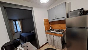 Cocina compacta con refrigerador, microondas y estufa. Hay un pequeño comedor con mesa y sillas.