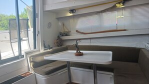 A compact, well-lit cabin with a small table and bench seating area, featuring a view through the window and a decorative item on the wall. - UNIQUE AND BEAUTIFUL "BONNE-VIE at SEA"<br> (Key Largo)