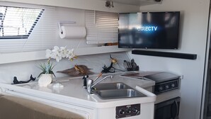 A compact kitchen with a built-in oven, a sink, and a flat-screen TV mounted above the counter. - UNIQUE AND BEAUTIFUL "BONNE-VIE at SEA"<br> (Key Largo)