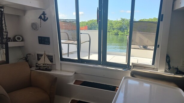 A room with a large window, a chair, a small table, and a shelf with decorative items. - UNIQUE AND BEAUTIFUL "BONNE-VIE at SEA"<br> (Key Largo)