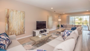 A modern living room with a large sofa, a flat-screen TV, and a coffee table. - Solterra Exec Villas- 6164bod (Davenport)