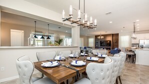 A dining area with a wooden table set for six, surrounded by tufted chairs. - Solara Resort Exec Villas- 9091sr (Kissimmee)