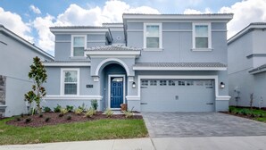 A two-story house with a blue front door, a garage, and a well-maintained lawn. - Champions Gate Exec Villas- 1670mvd (Davenport)