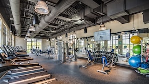 Une salle de sport équipée de tapis de course, d’appareils de musculation et de ballons d’exercice.