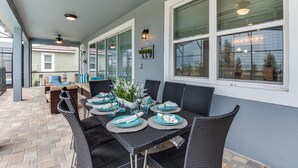 Un patio couvert avec une table à manger pour quatre personnes, entouré de chaises en osier.