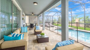 Un patio couvert avec des sièges d’extérieur, une piscine et une vue sur le jardin arrière.