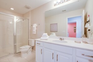 A modern bathroom with a glass shower enclosure, a white toilet, and a vanity with a large mirror. - Solara Resort Exec Villas- 1542cpc (Kissimmee)