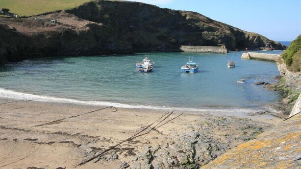 A coastal scene with boats anchored near a breakwater, a sandy beach, and rocky terrain. - Harbour Loft - Two Bedroom Apartment, Sleeps 4 (Port Isaac)