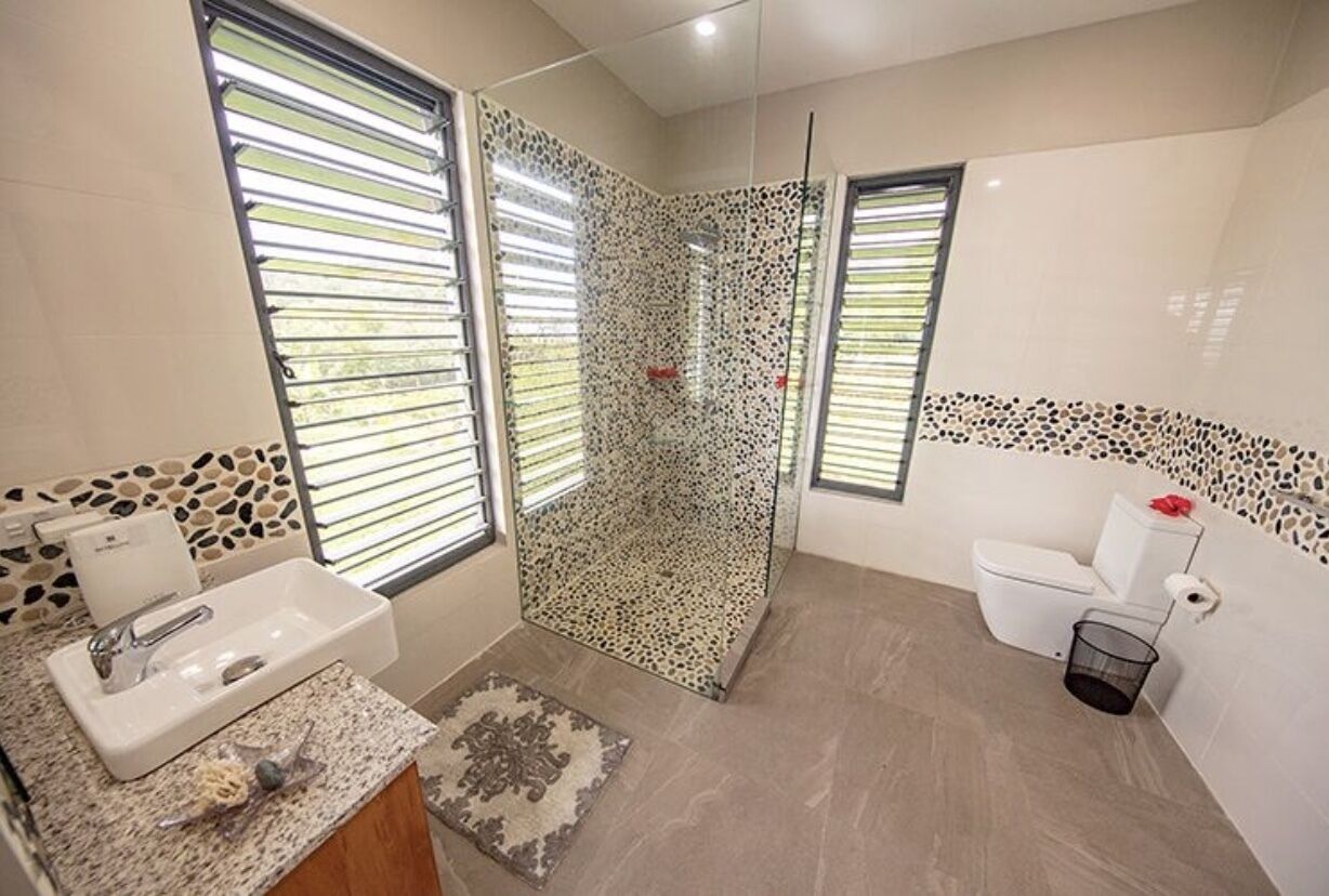 Een moderne badkamer met een douche, toilet en wastafel.