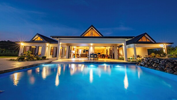 Et moderne hus med swimmingpool, store vinduer og en overdækket patio.