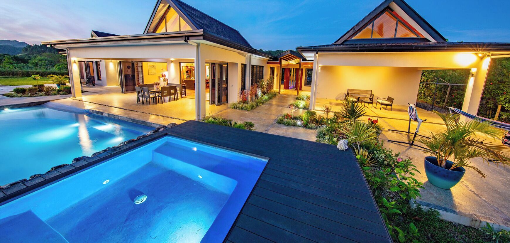 Ein modernes Haus mit Swimmingpool, Sitzgelegenheiten im Freien und einem gepflegten Garten.