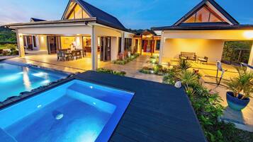 Ein modernes Haus mit Swimmingpool, Sitzgelegenheiten im Freien und einem gepflegten Garten.