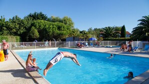 A swimming pool with people around it, including a person diving into the pool.
