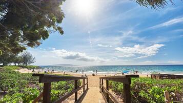 A wooden pathway leading to a beach with clear skies and ocean view.