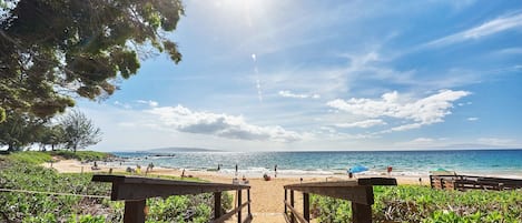 Un sentier en bois mène à une plage, où le ciel est dégagé et où l’on peut admirer l’océan.