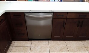 A kitchen with a dishwasher, wooden cabinets, and a white countertop.