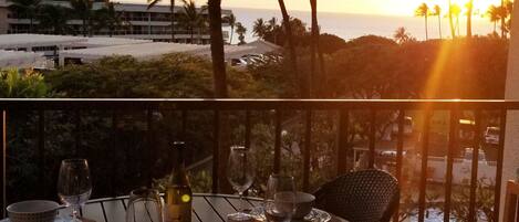 A dining table set for two with a view of the ocean and palm trees.
