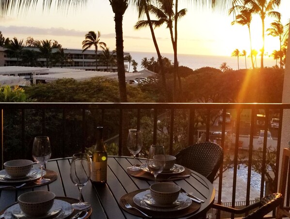 A dining table set for two with a view of the ocean and palm trees. - Beautiful Ocean View! Newly renovated kitchen and 2 Air Conditioners (Kihei)