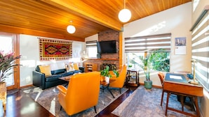 A modern living room with a fireplace, a television, and a dining area with a table and chairs. - Hilltop Hideaway, cozy forest retreat, Portland (Portland)