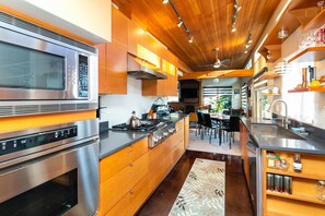 A modern kitchen with stainless steel appliances, wooden cabinetry, and a central island. - Hilltop Hideaway, cozy forest retreat, Portland (Portland)