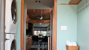 A laundry area with a washing machine and dryer, a kitchen with a dining area, and a wooden ceiling. - Hilltop Hideaway, cozy forest retreat, Portland (Portland)