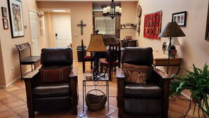 Una sala de estar con dos sillones de cuero, una mesa de comedor y una araña.