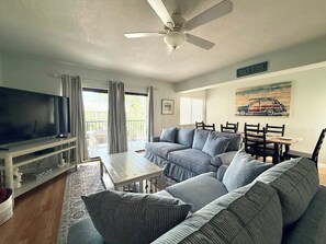 Una sala de estar con sofá, televisor, ventilador de techo, mesa de comedor y sillas.