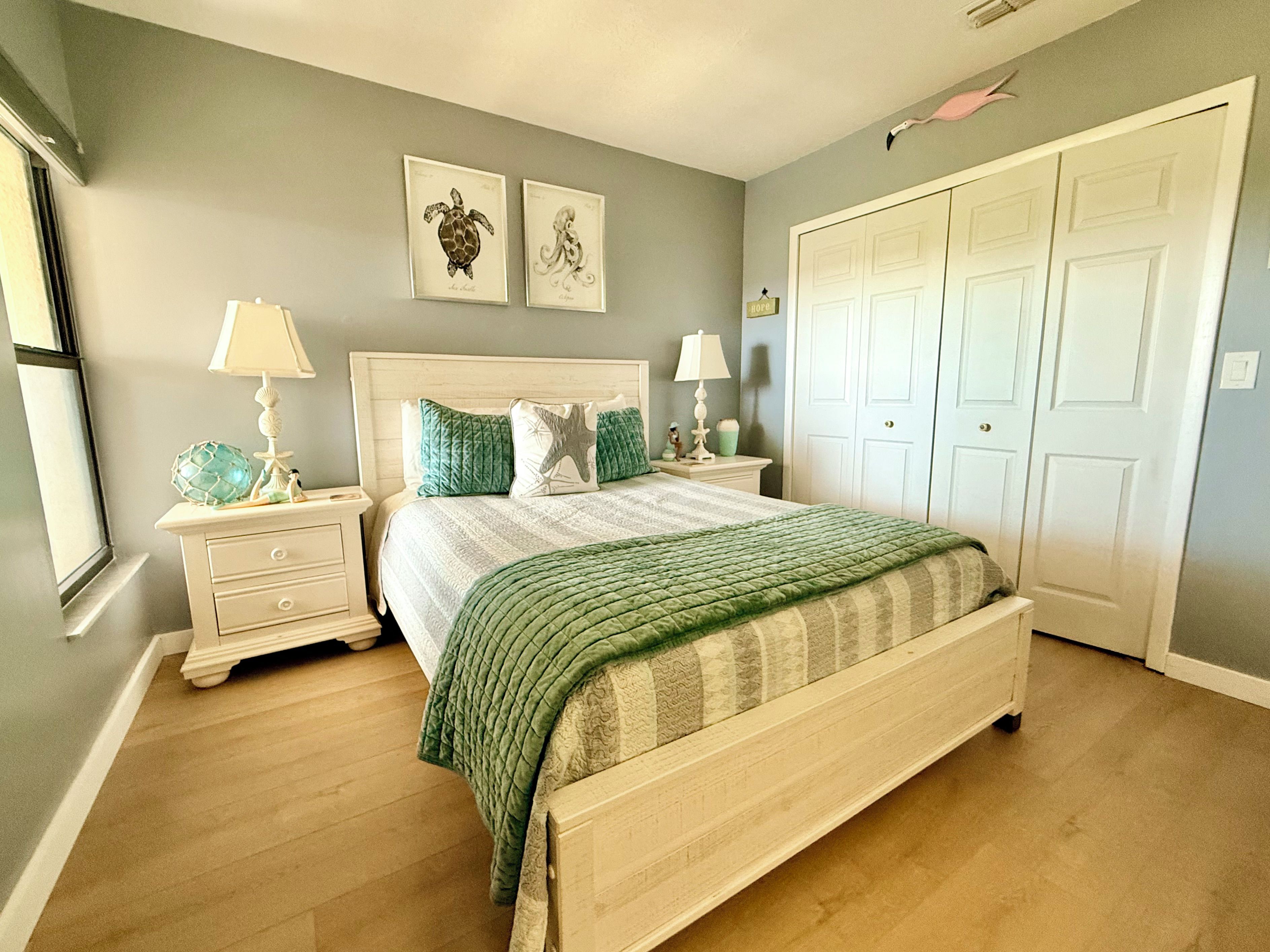 A bedroom with a bed, nightstands, a dresser, a closet, and two wall-mounted pictures.