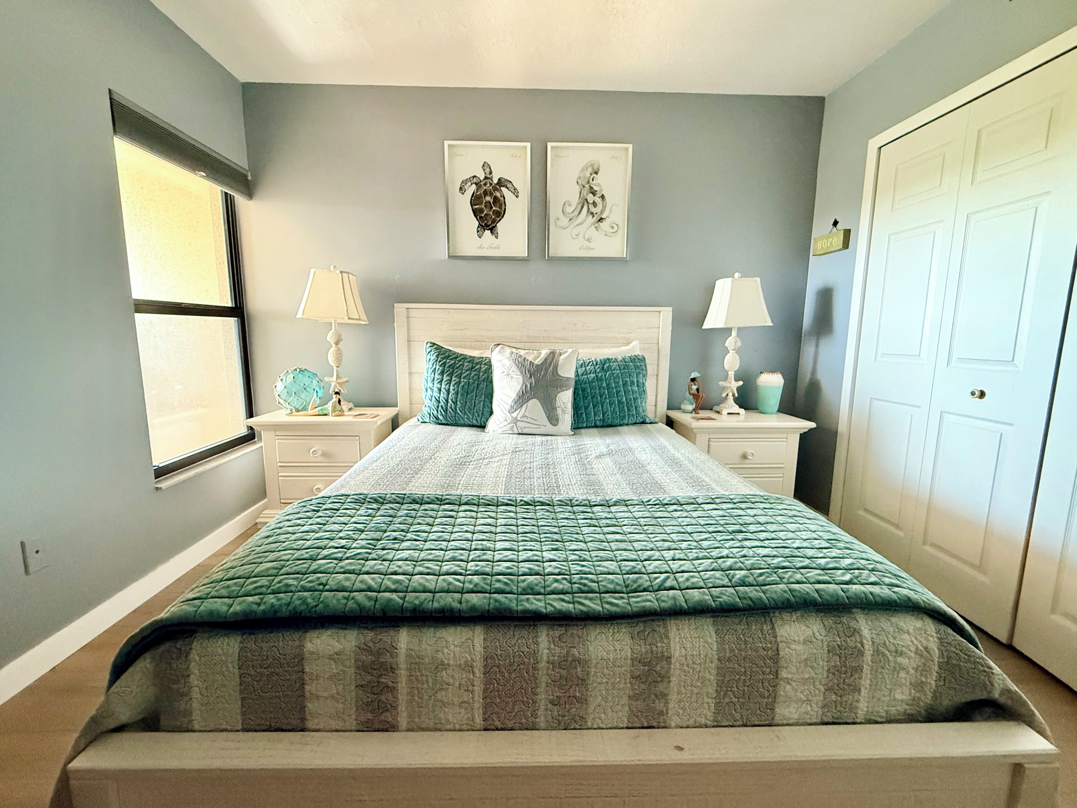 A bedroom with a bed, two nightstands, a window, and a door.