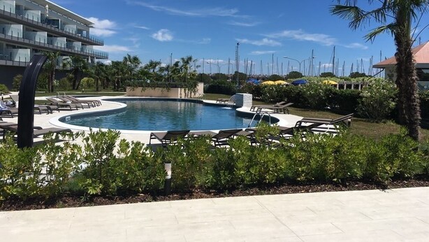 A modern hotel with a pool area, including lounge chairs and a palm tree.