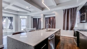 A modern kitchen with a marble countertop, stainless steel sink, and a built-in oven.