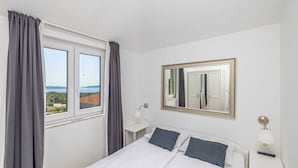 Een hotelkamer met een bed, een grote spiegel, een raam met gordijnen en uitzicht op het landschap.