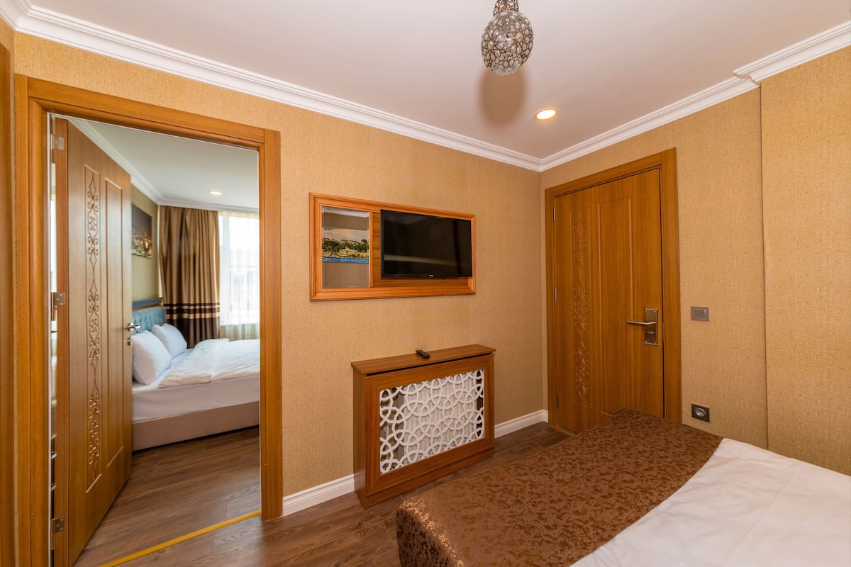 A hotel room with a bed, a TV, a wooden door, and a console table.