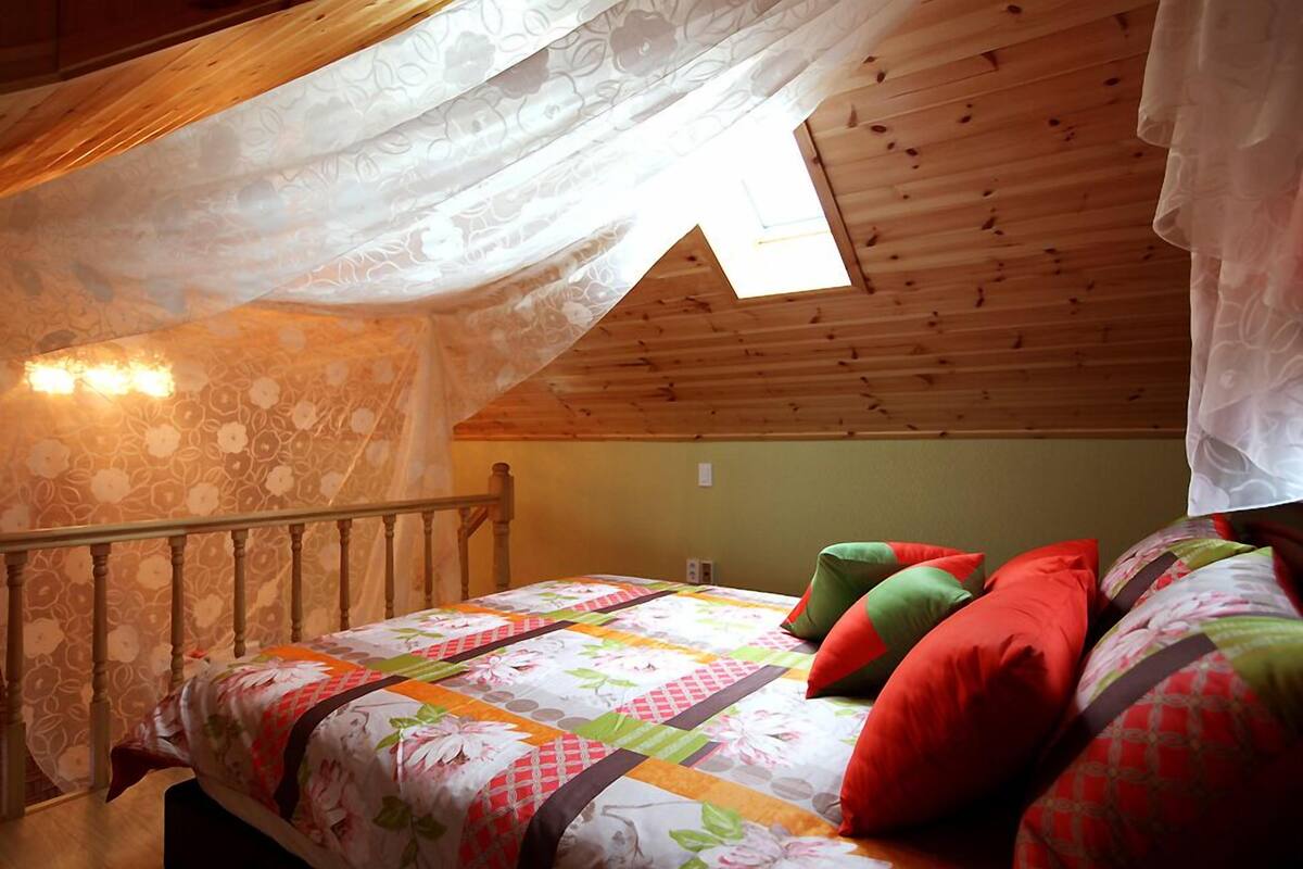 Un dormitorio con techo de madera, una cama con colcha floral y una ventana con marco de madera.