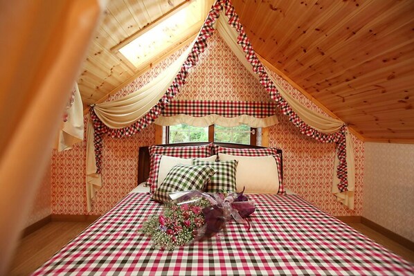 Un dormitorio acogedor con una colcha a cuadros, un ramo de flores y una ventana con cortinas.