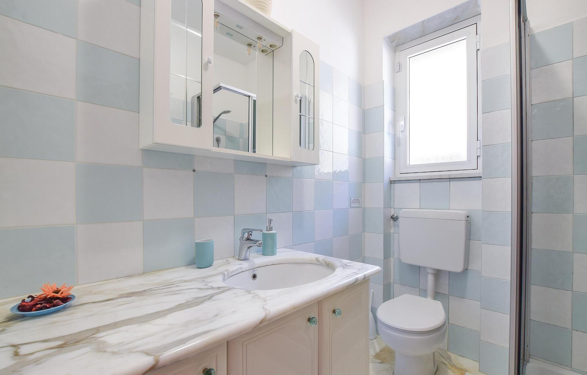 A bathroom with a marble sink, a toilet, and a shower area.