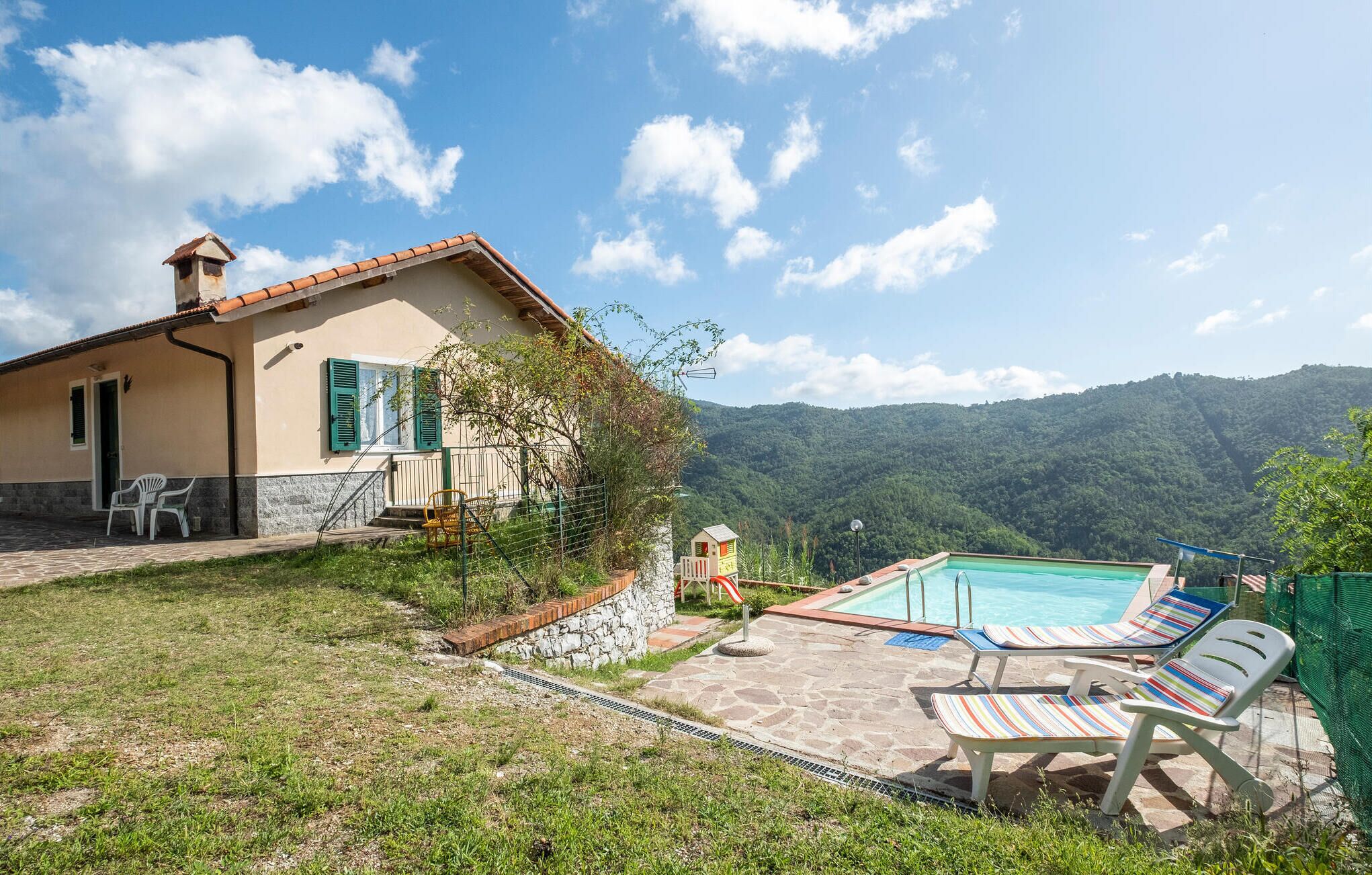 Una casa con piscina, mobiliario exterior y vistas a las montañas.