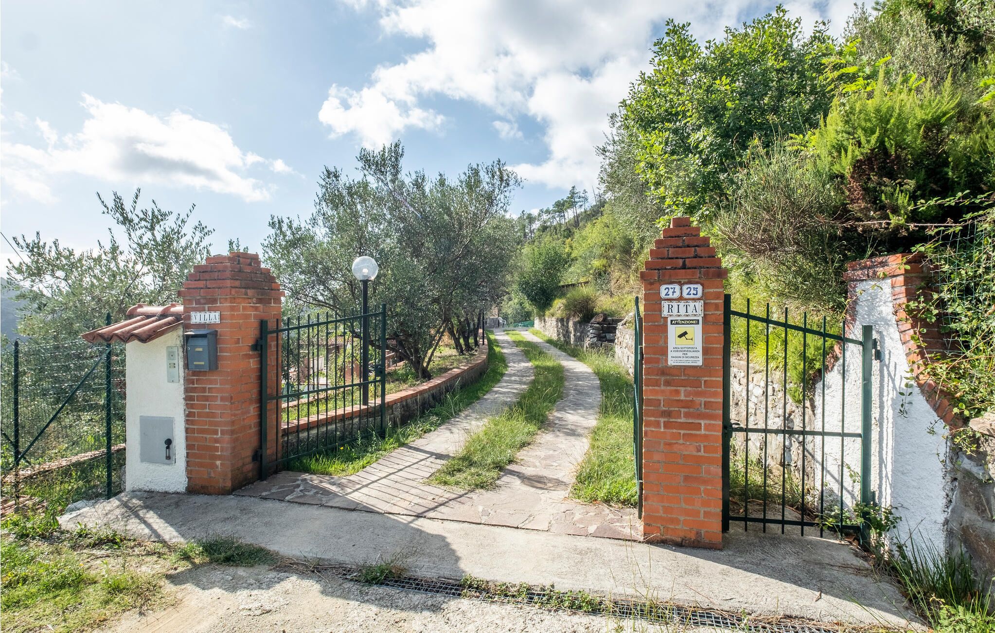 Un cancello chiuso con un muro in mattoni e un cartello che indica 'Rita'.