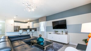 A modern living room with a black leather sofa, a glass coffee table, and a white cabinet. - Champions Gate Exec Villas- 1686mvd (Davenport)