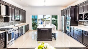 A modern kitchen with dark cabinetry, stainless steel appliances, and a central island. - The White House TCI and Kenard Cruises Luxury Yacht charter vacation Package  (Providenciales)