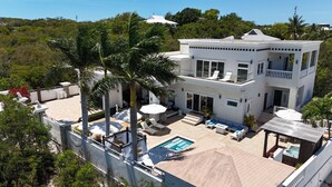 A two-story house with a pool, outdoor seating, and palm trees. - The White House TCI and Kenard Cruises Luxury Yacht charter vacation Package  (Providenciales)