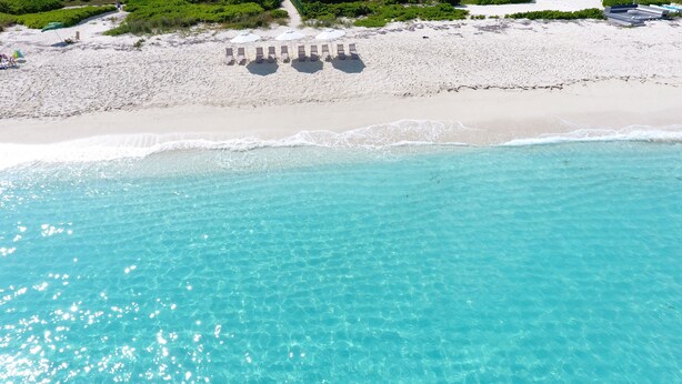 A beach with clear turquoise water, a row of sun loungers, and a path leading to the water. - The White House TCI and Kenard Cruises Luxury Yacht charter vacation Package  (Providenciales)