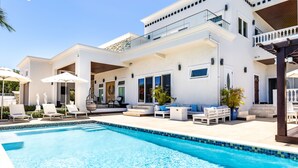 A modern house with a swimming pool, outdoor seating, and a covered patio area. - The White House TCI and Kenard Cruises Luxury Yacht charter vacation Package  (Providenciales)
