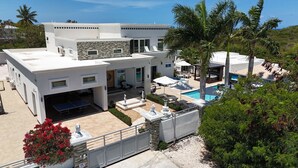 A modern two-story house with a swimming pool, outdoor seating, and a fenced patio area. - The White House TCI and Kenard Cruises Luxury Yacht charter vacation Package  (Providenciales)
