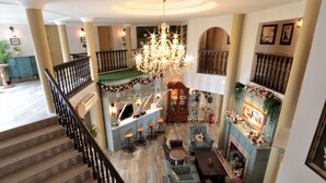 Eine großzügige Lobby mit einer prachtvollen Treppe, einem Barbereich und einem Kamin.
